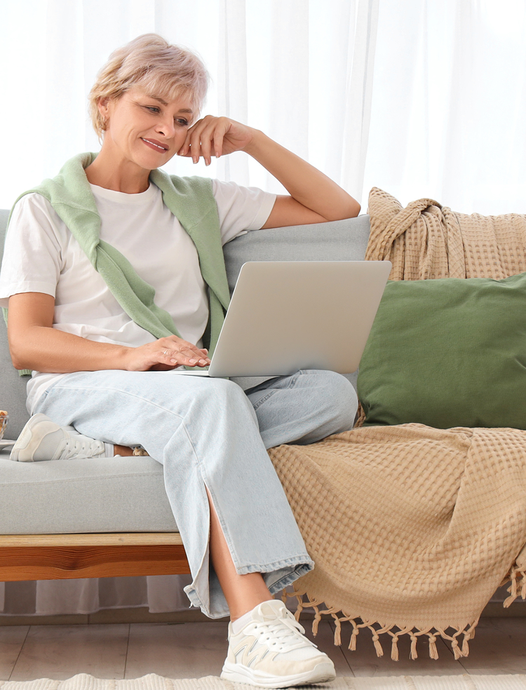 Woman sitting on sofa using Windows 11 compatible laptop