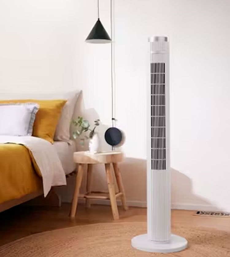 Dimplex 117cm white tower fan with built-in night light standing on woven rug beside bed with mustard bedding and wooden bedside table 