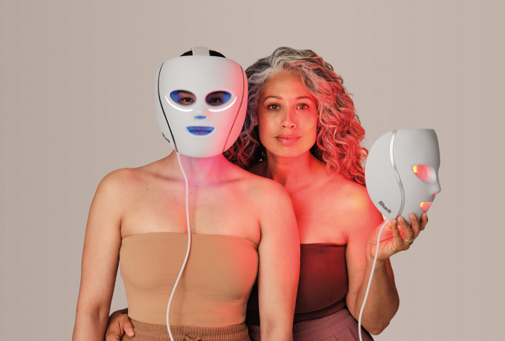 Two women posing with red and blue LED light therapy Shark face masks for skincare