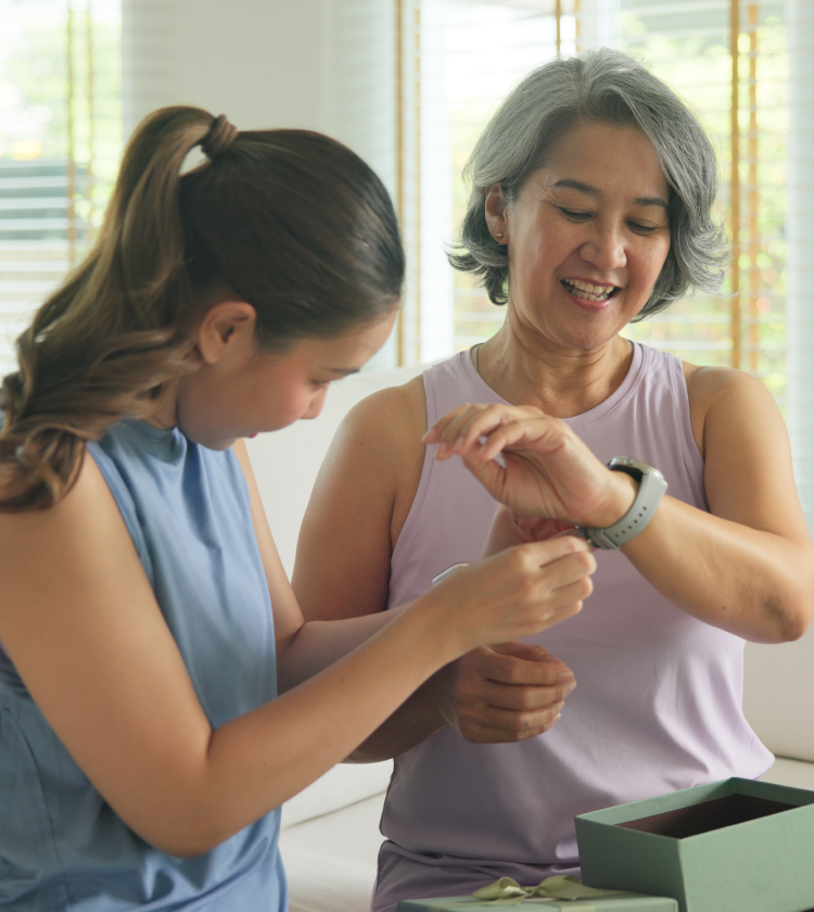 Happy mother and daughter smiling while trying on smartwatch as a gift
