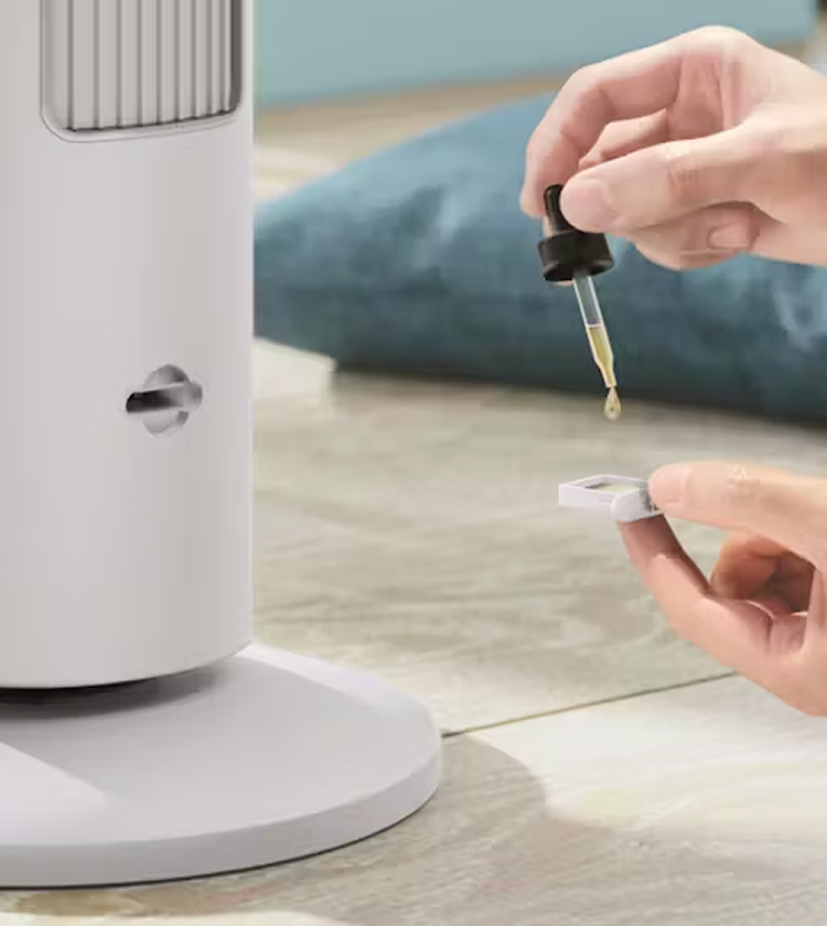 Philips 5000 Series White Tower Fan with essential oil diffuser tray being filled with oil using dropper, shown in close-up 