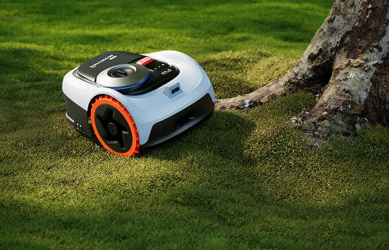 Segway Navimow robotic lawn mower navigating around a tree on an uneven lawn
