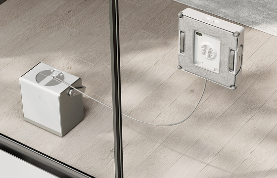 Robot window cleaner secured to exterior glass with a safety tether connected to its base station indoors