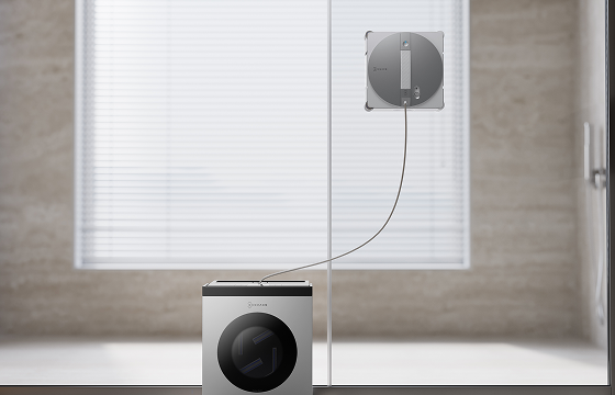Robot window cleaner attached to a shower screen and connected by cable to its portable cleaning station