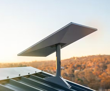 Starlink satellite dish mounted on metal rooftop with hills in background