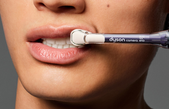 Dyson CameraJet™ electric toothbrush using its built-in macro camera to inspect a woman’s teeth 
