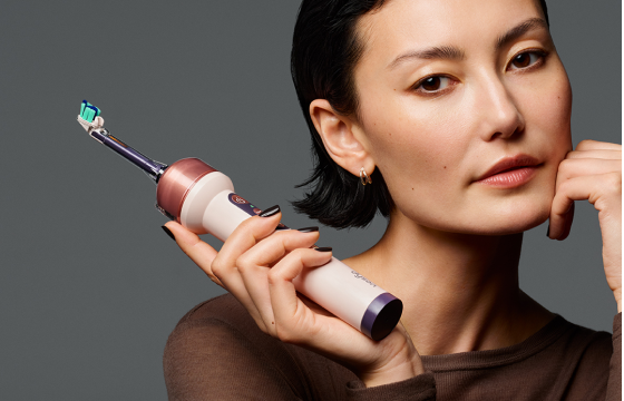 Woman holding the Dyson CameraJet™ electric toothbrush with dual-bristle brush head and water tank 