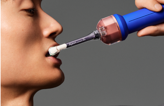 Woman using the Dyson CameraJet™ electric toothbrush with targeted jet flossing 