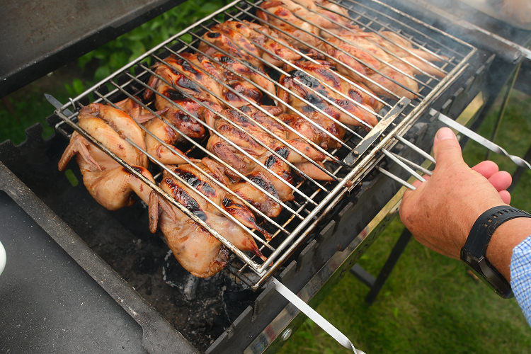 Whole chickens cooking over hot coals on a charcoal BBQ rotisserie 