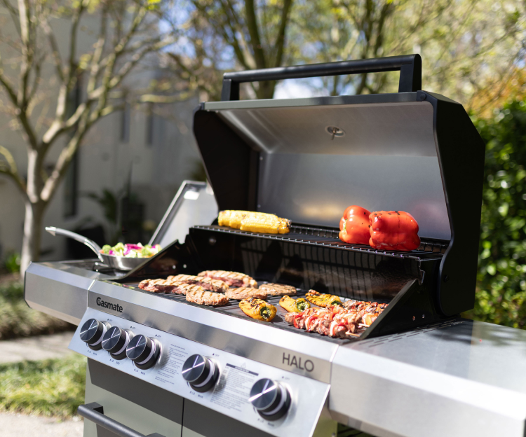 Gasmate gas BBQ grilling meat, corn and capsicum in a backyard 