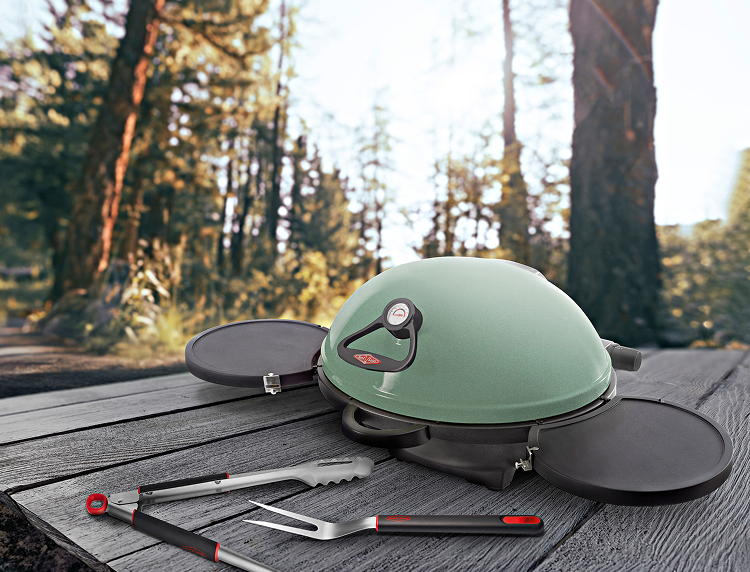Compact portable BBQ with grilling tools on a picnic table in the forest 